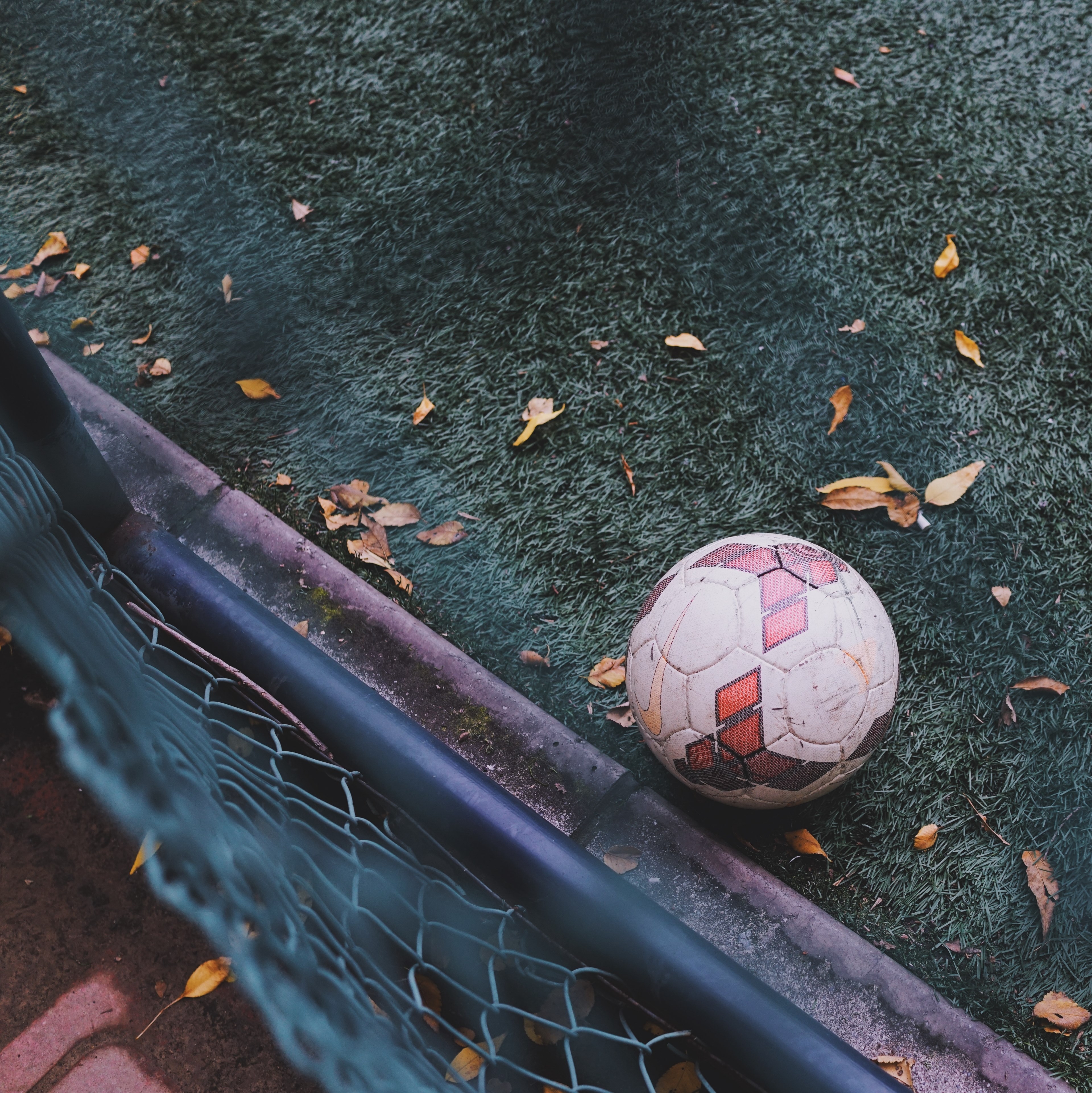 3840x3850 Wallpaper / view over the fence on the soccer ball sitting on a green turf pitch, football on fall ground 4k wallpaper free download, Phone